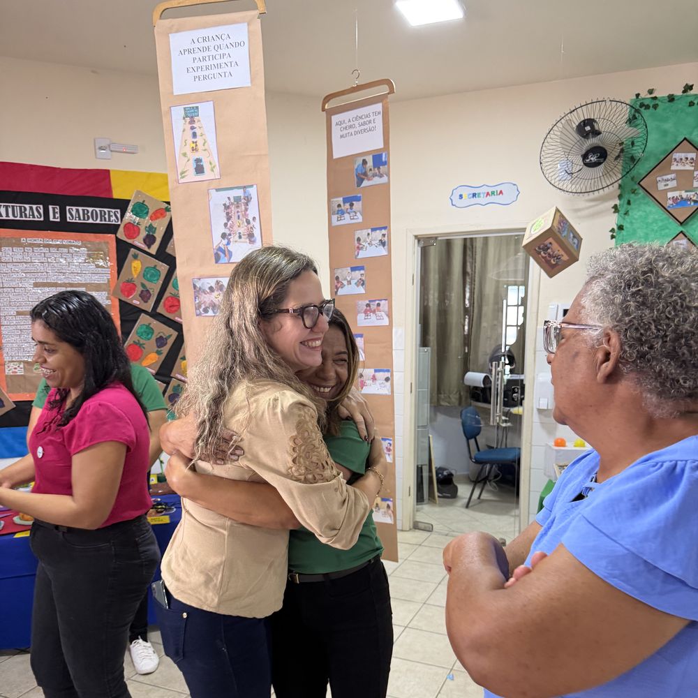 Professora Mariene abraçando uma professora durante visita a uma escola